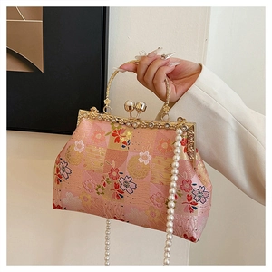 Detailed close-up of pink cherry blossom embroidery on evening bag with pearl clasp