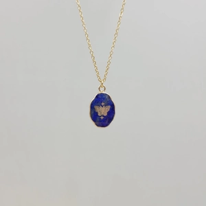 Detail of gold stainless steel necklace with blue stone pendant and engraved butterfly