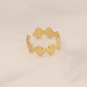 Detail shot of golden clover link ring with hammered texture on marble surface