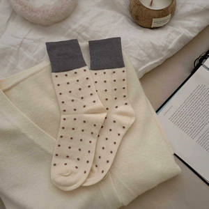 Detailed view of beige polka dot mid-calf socks with grey ribbed cuffs in a vintage setting