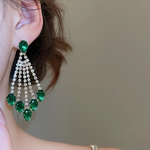 Detail van hangende smaragdgroene kwastjes oorbellen met glinsterende strass-steentjes
