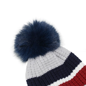 Detail of colorful striped knit hat featuring a fluffy faux fur pom-pom on top