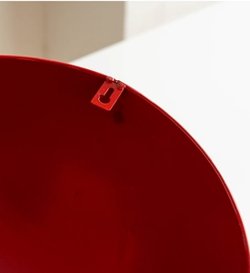 Detail of red metal wall decoration showing the sturdy hanging hole and glossy finish
