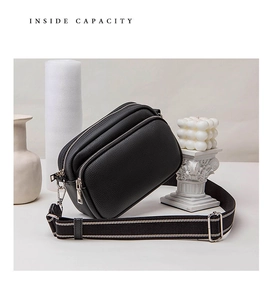 Detail of black lychee leather crossbody bag with triple zippers and wide strap