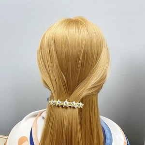 Close-up of golden star-shaped metal hair clip securing a half-up hairstyle on long blonde hair