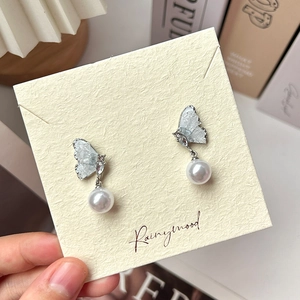 Detail of silver butterfly earrings with pearls and crystals on a branded jewelry card
