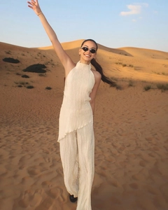 Detailed texture of pleated cream halter top and wide-leg trousers set in desert setting