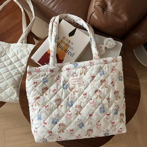 Close-up of quilted floral tote bag with cute animal patterns and woven label detail