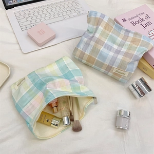 Detailed interior of large plaid cosmetic bag with brushes and skincare products