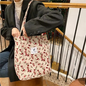 Detail of floral corduroy tote bag showing metal snap button and vintage floral pattern