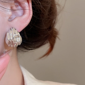 Macro shot of silver-toned textured dome earrings with vertical striped metal details