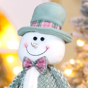 Nahaufnahme der minzgrünen Weihnachts-Schneemann-Puppe mit karierter Schleife und Bokeh-Licht
