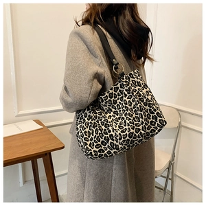 Detail of leopard print canvas tote bag with black leather strap and gold rings