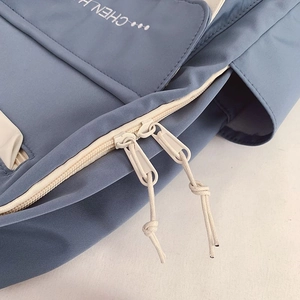 Detail of blue nylon backpack featuring a sturdy beige double zipper with pull cords