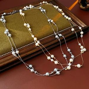 Detail of vintage layered beaded necklaces in gold and silver finishes on dark wood