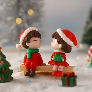 Miniature Christmas couple figurines sitting on a bench in a festive snow scene