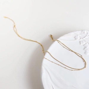 Macro detail of 18K gold plated double layer necklace with snake and bead chains