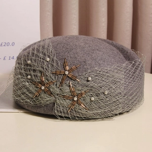 Detail of wool beret featuring light green mesh veil with pearls and beaded floral stars