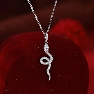 Detailed macro view of S925 silver snake pendant with white zircon and green eyes on velvet