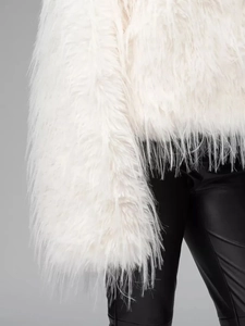 Close-up of plush white faux fur jacket texture with soft long-pile synthetic fibers
