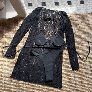 Detailed flat lay of a 3-piece black lace long-sleeve cover-up with bikini set