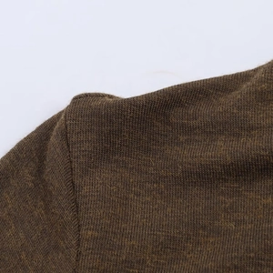 Détail macro montrant la couture d'épaule et la maille d'un haut à col montant marron foncé