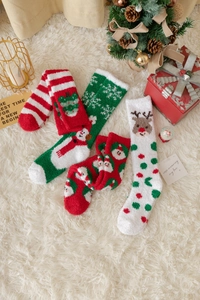 Nahaufnahme von dicken Korallenfleece-Weihnachtssocken mit Festtagsmustern auf Plüsch