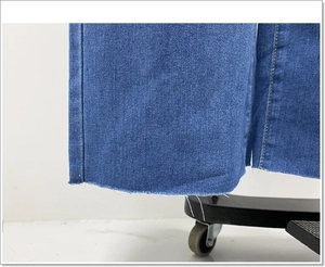 Detailopname van de gerafelde zoom en gele stiksels op de blauwe denim jeans met wijde pijpen