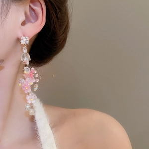 Detail of elegant floral tassel earring featuring pink petals and crystals on model