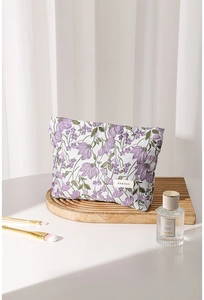 Macro view of floral canvas makeup bag with H&R BAG logo on wooden tray under natural light