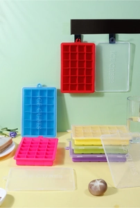 Multiple colors of 24-grid silicone ice cube trays with lids stacked against a green wall