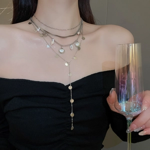 Detail of layered silver seashell necklace with round discs and long Y-shaped tassels