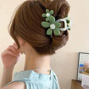 Pinza per capelli a fiore verde con perla mostrata su un'acconciatura da donna