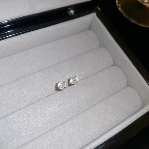 Macro view of four-prong set sparkling zircon earrings in a gray velvet jewelry box