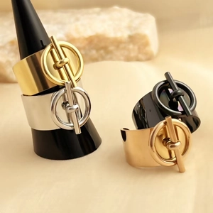 Minimalist gold, silver, and black stainless steel buckle rings displayed on a stone base