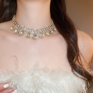 Close-up of golden fringe necklace with teardrop rhinestones on model's neck