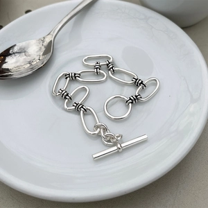 Detail of 925 sterling silver chain bracelet with OT toggle clasp on a white plate