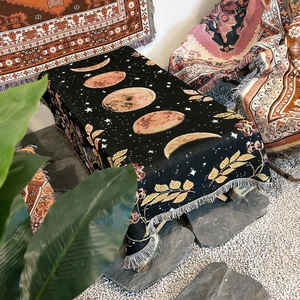 Detail of woven black camping blanket with lunar phases and fringed edges design