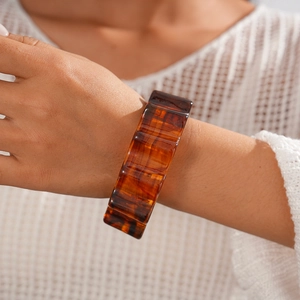 Detail of amber acrylic square bangle showing unique marbled texture on model's wrist