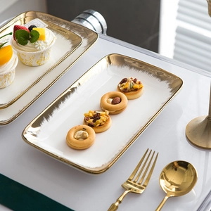 Modern white ceramic steak plates with gold brushed edges and elegant dessert setup