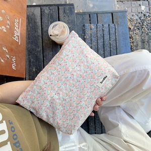 Close-up of floral fabric pouch with Sozakka brand label on a wooden bench