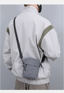 Rear view of minimalist gray crossbody bag with adjustable strap worn by male model