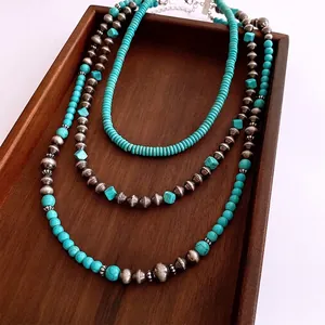 Vintage bohemian three-layer turquoise and silver bead necklace on dark wood background