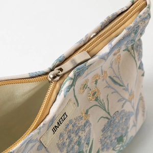 Dettaglio ravvicinato del tessuto jacquard floreale con cerniera dorata ed etichetta