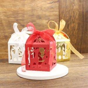 Close-up of laser-cut reindeer Christmas favor boxes in red, white and gold with ribbons