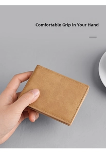 Close-up of a slim tan matte leather wallet held in hand showing fine stitching detail