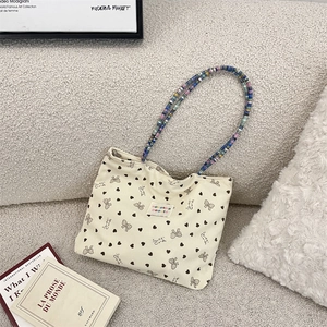 Detail of corduroy tote bag featuring colorful beaded handles and sweet ribbon patterns