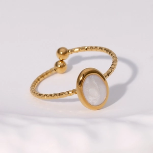 Dettaglio anello dorato regolabile con inserto ovale bianco e texture a corda intrecciata