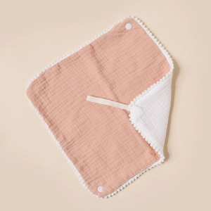 Detail of baby cotton gauze bib with white pom-pom trim and snap button closure