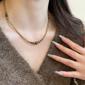 Tiger eye stone beaded necklace styled on a brown sweater for a vintage aesthetic look